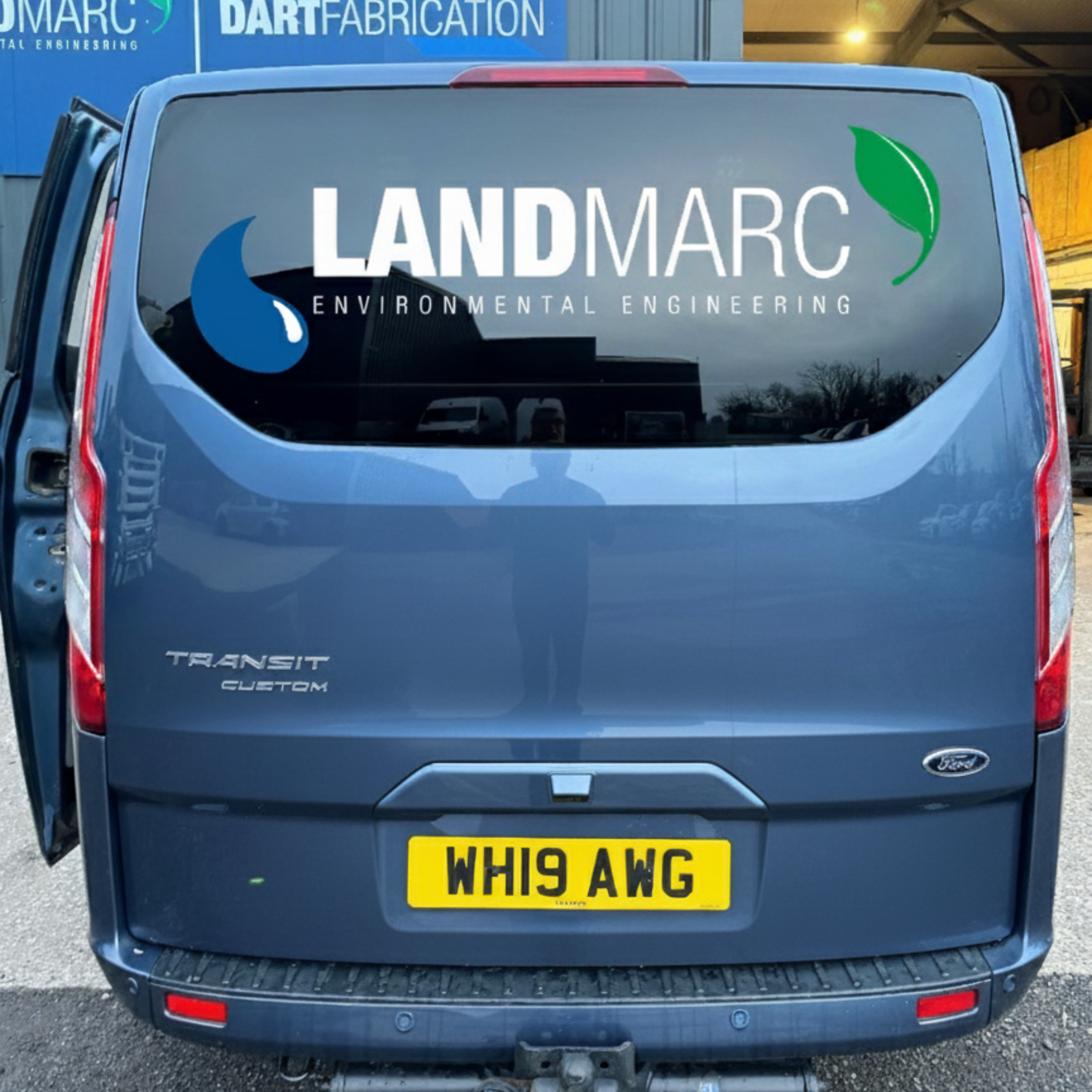 Blue Ford Transit Custom Van with Landmarc vehicle graphics logo applied to rear window, installed in Halwell, South Devon.