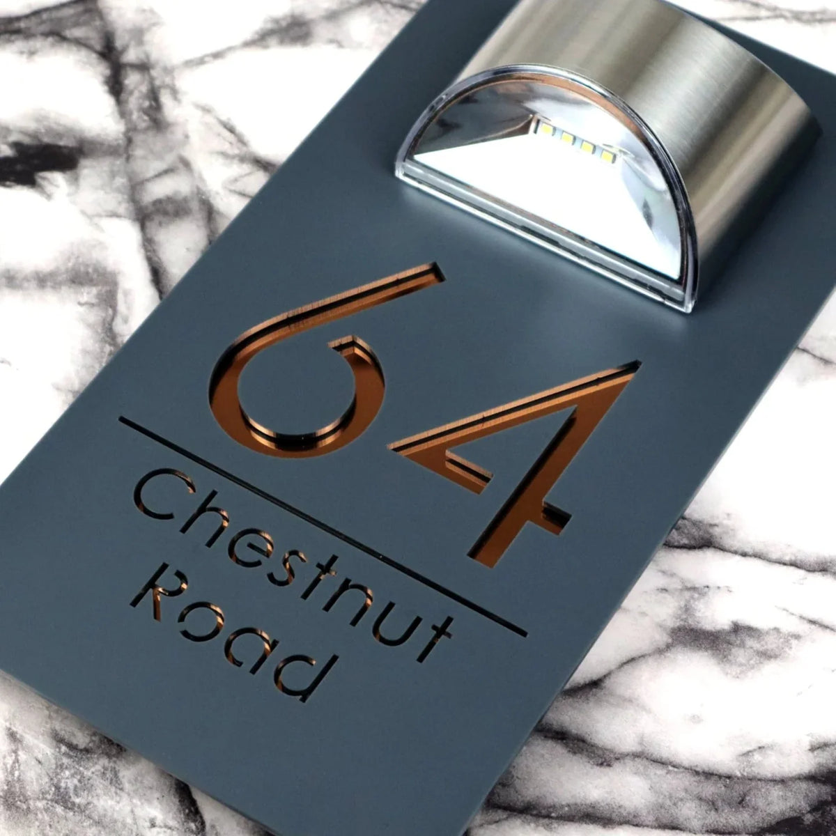 Close-up of copper mirrored lettering on the matt grey luxury solar LED house sign