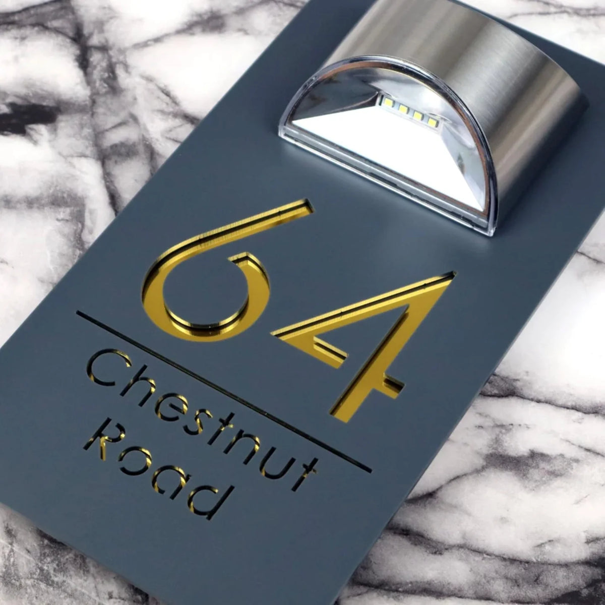 Close-up of gold mirrored lettering on the matt grey luxury solar LED house sign